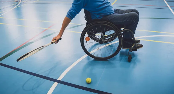 Volwassen man met een lichamelijke beperking die gebruik maakt van rolstoel tennissen op een indoor tennisbaan — Stockfoto