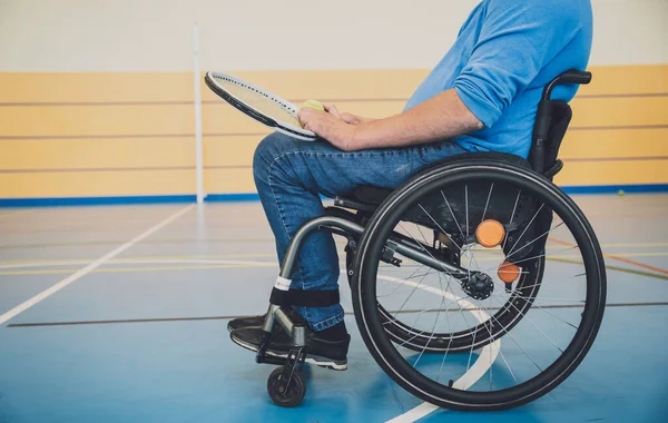Homem adulto com deficiência física que usa cadeira de rodas jogando tênis em quadra de tênis indoor — Fotografia de Stock