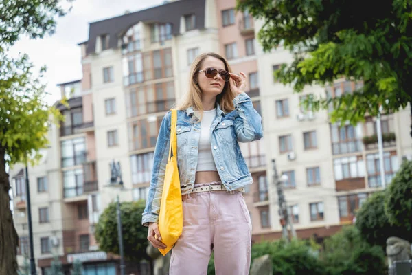 Jeune belle femme avec sac écologique en lin sur fond de ville. — Photo