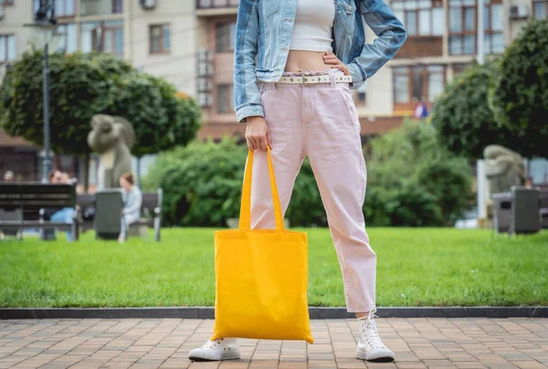 Jeune belle femme avec sac écologique en lin sur fond de ville. — Photo