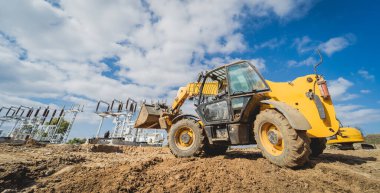 Tekerlek yükleyici kazıcı inşaat alanında çalışıyor.