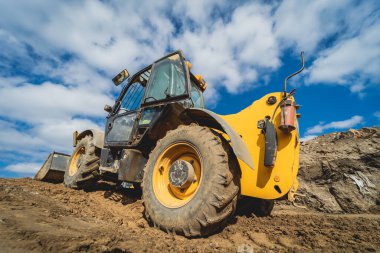 Tekerlek yükleyici kazıcı inşaat alanında çalışıyor.
