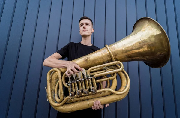 Young street musician playing the tuba near the big blue wall — Fotografia de Stock