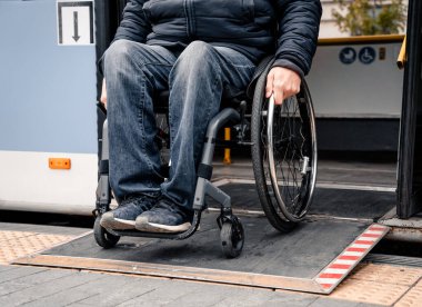 Fiziksel engelli kişiler toplu taşımadan erişilebilir bir rampayla çıkıyorlar..