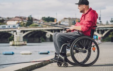 Balıkçı iskelesinden tekerlekli sandalyede balık tutan fiziksel engelli biri..