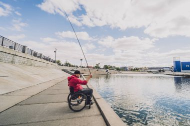 Balıkçı iskelesinden tekerlekli sandalyede balık tutan fiziksel engelli biri..