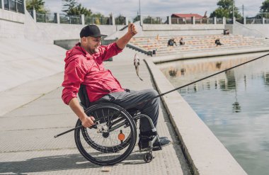 Balıkçı iskelesinden tekerlekli sandalyede balık tutan fiziksel engelli biri..