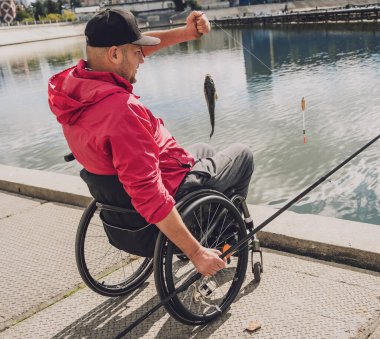 Balıkçı iskelesinden tekerlekli sandalyede balık tutan fiziksel engelli biri..