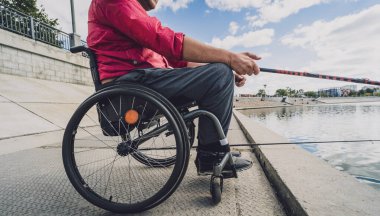 Balıkçı iskelesinden tekerlekli sandalyede balık tutan fiziksel engelli biri..