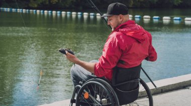 Balıkçı iskelesinden tekerlekli sandalyede balık tutan fiziksel engelli biri..