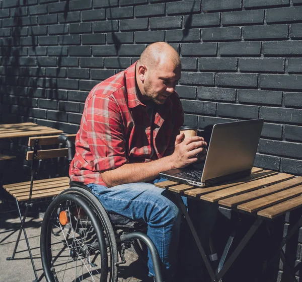 Sokak kafesinde çalışan ve tekerlekli sandalye kullanan fiziksel engelli bir serbest çalışan.