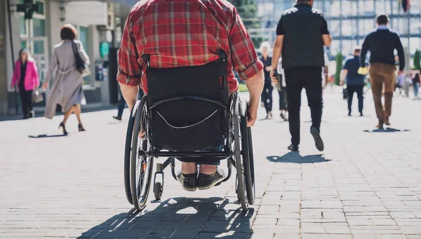 Sokakta tekerlekli sandalyeyle yürüyen fiziksel engelli bir genç. — Stok fotoğraf