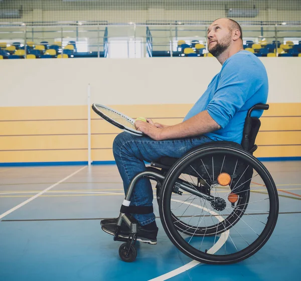 Erwachsener Mann mit körperlicher Behinderung, der Rollstuhl benutzt, um Tennis auf dem Tennisplatz zu spielen — Stockfoto