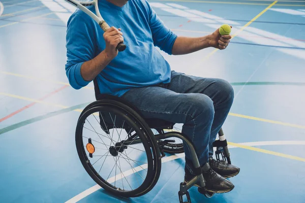 Erwachsener Mann mit körperlicher Behinderung, der Rollstuhl benutzt, um Tennis auf dem Tennisplatz zu spielen — Stockfoto