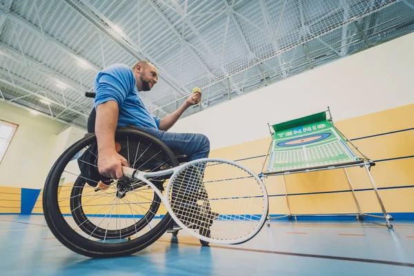 Erwachsener Mann mit körperlicher Behinderung, der Rollstuhl benutzt, um Tennis auf dem Tennisplatz zu spielen — Stockfoto