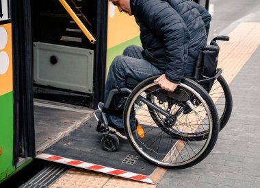 Fiziksel engelli bir kişi erişilebilir bir rampayla toplu taşımaya giriyor.