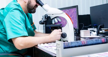 Laboratuvar asistanı modern laboratuvarda mikroskopla çalışıyor..
