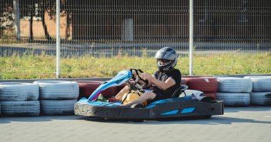 Genç bir adam pistte go kart kullanıyor.