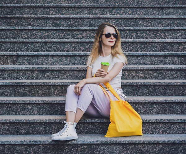 Genç ve güzel bir kadın. Arka planda keten bir çanta var..