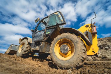 Tekerlek yükleyici kazıcı inşaat alanında çalışıyor.