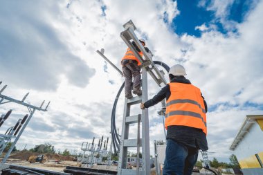 Yüksek voltajlı kablo döşeyen iki elektrikçi işçi