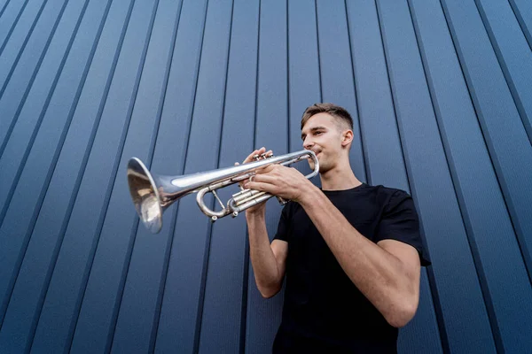 Jeune musicien de rue jouant de la trompette près du grand mur bleu — Photo