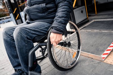 Fiziksel engelli kişiler toplu taşımadan erişilebilir bir rampayla çıkıyorlar..