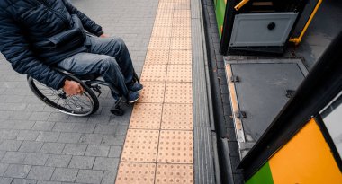 Fiziksel engelli bir kişi erişilebilir bir rampayla toplu taşımaya giriyor.