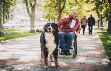 Köpeğiyle tekerlekli sandalye kullanan fiziksel engelli genç adam..