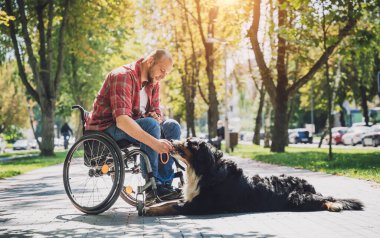 Köpeğiyle tekerlekli sandalye kullanan fiziksel engelli genç adam..