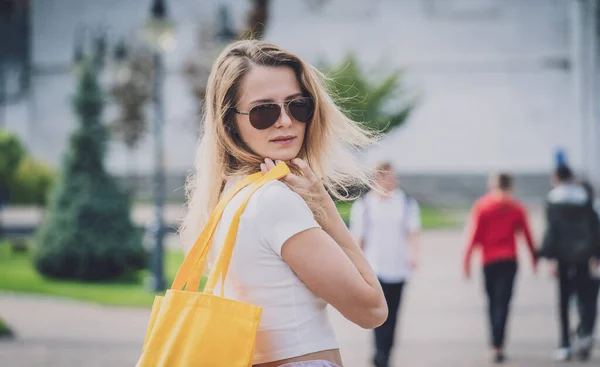 Jeune belle femme avec sac écologique en lin sur fond de ville. — Photo