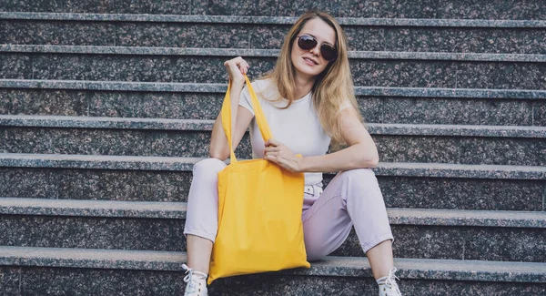 Jeune belle femme avec sac écologique en lin sur fond d'escalier. — Photo