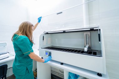 Laboratuvar asistanı modern laboratuvarda otomatik çoklu slayt boyayıcısıyla çalışıyor..