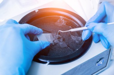 Laboratuvar asistanı bir döner mikro bölüm üzerinde çalışıyor ve mikroskop slaytları yapıyor