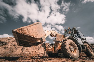 Tekerlek yükleyici kazıcı inşaat alanında çalışıyor.