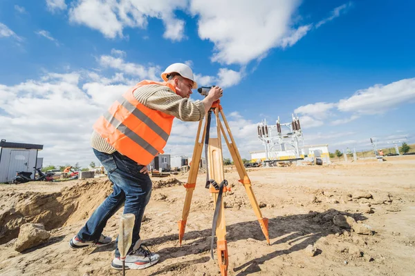 Undersökare arbetare med teodolitutrustning på byggarbetsplatsen — Stockfoto