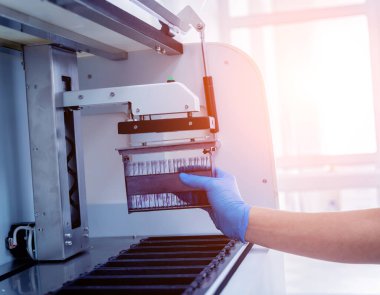 Laboratuvar asistanı modern laboratuvarda otomatik çoklu slayt boyayıcısıyla çalışıyor..