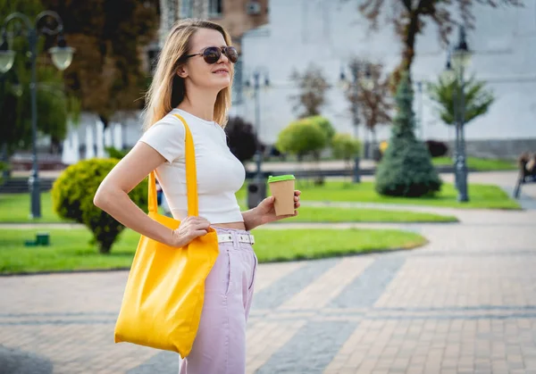 Jeune belle femme avec sac écologique en lin sur fond de ville. — Photo