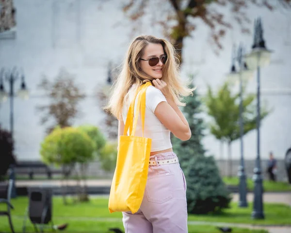 Νεαρή όμορφη γυναίκα με λινό οικολογική τσάντα στο φόντο της πόλης. — Φωτογραφία Αρχείου
