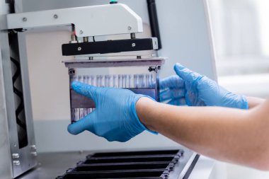 Laboratuvar asistanı modern laboratuvarda otomatik çoklu slayt boyayıcısıyla çalışıyor..