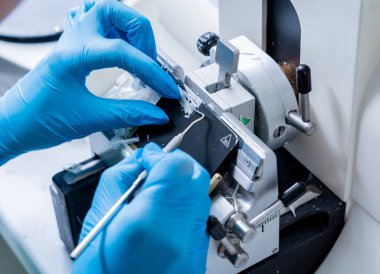 Laboratuvar asistanı bir döner mikro bölüm üzerinde çalışıyor ve mikroskop slaytları yapıyor