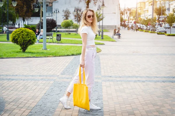 Jeune belle femme avec sac écologique en lin sur fond de ville. — Photo