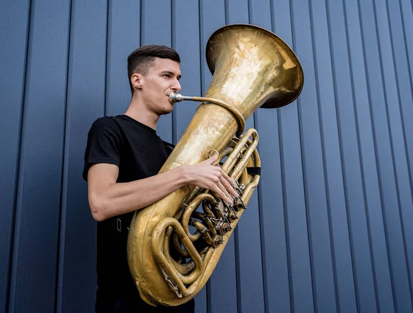 Joven músico callejero tocando la tuba cerca de la gran pared azul — Foto de Stock