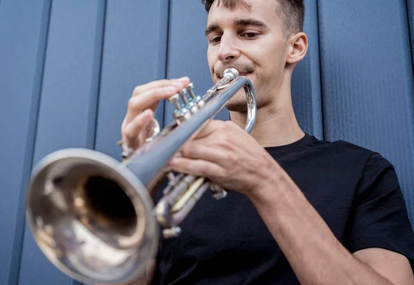 Jeune musicien de rue jouant de la trompette près du grand mur bleu — Photo