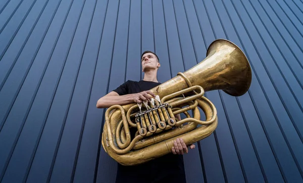 Young street musician playing the tuba near the big blue wall — Fotografia de Stock