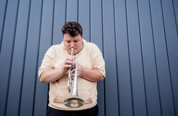 Jeune musicien de rue jouant de la trompette près du grand mur bleu — Photo