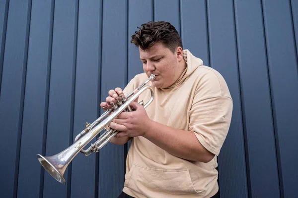 Jeune musicien de rue jouant de la trompette près du grand mur bleu — Photo