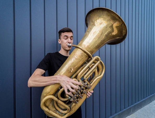 Joven músico callejero tocando la tuba cerca de la gran pared azul — Foto de Stock