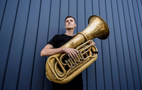 Young street musician playing the tuba near the big blue wall — Fotografia de Stock