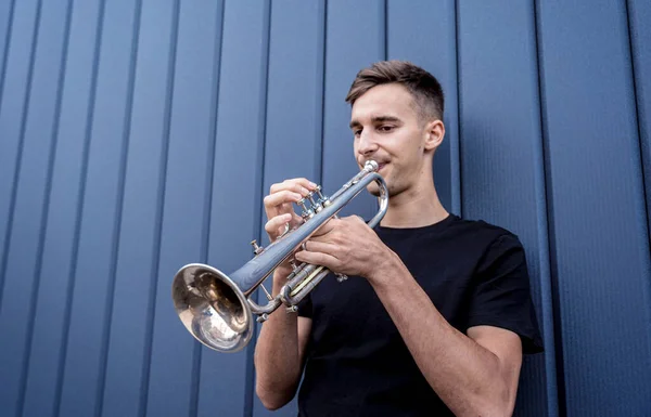 Joven músico callejero tocando la trompeta cerca de la gran pared azul — Foto de Stock